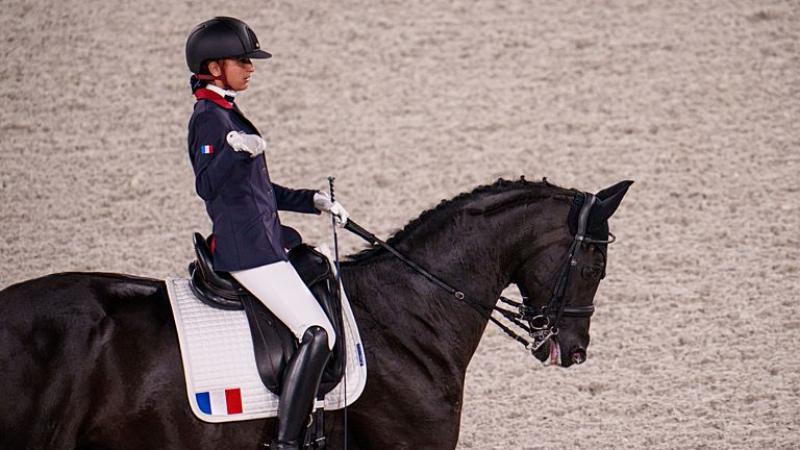 A female Para equestrian athlete rides a horse
