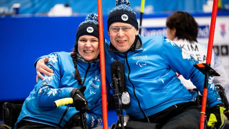 A male and female wheelchair curling athletes pose for a photo