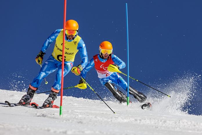 A male alpine skier is competing with his guide