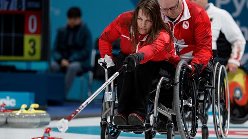 A female wheelchair curling athlete is in action at the PyeongChang 2018 Paralympic Winter Games