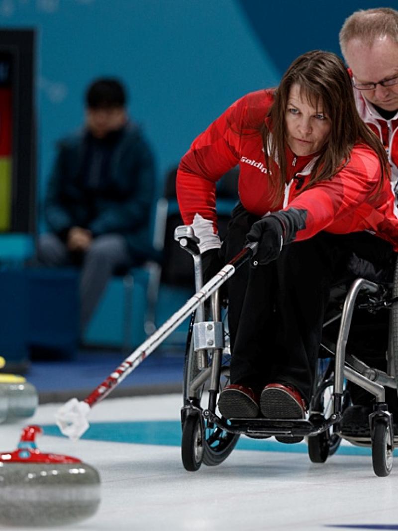 A female wheelchair curling athlete is in action at the PyeongChang 2018 Paralympic Winter Games