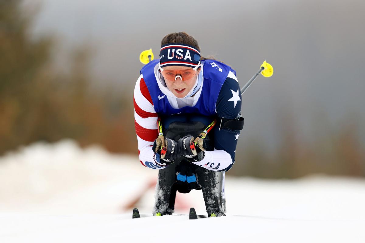 A female sit-skier is competing in a cross-country race