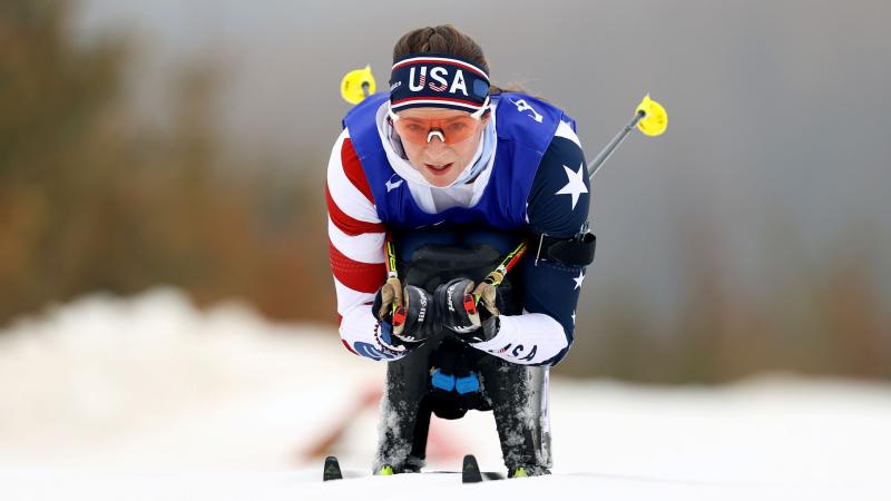 A female sit-skier is competing in a cross-country race