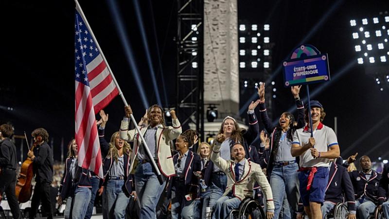 A group of athletes wearing a blue or white jacket are parading during the Opening Ceremony of Paris 2024