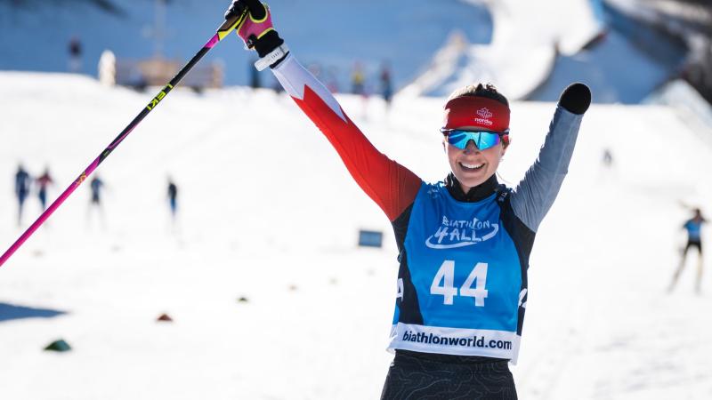 A female Para athlete wearing a ski gear raises her arms