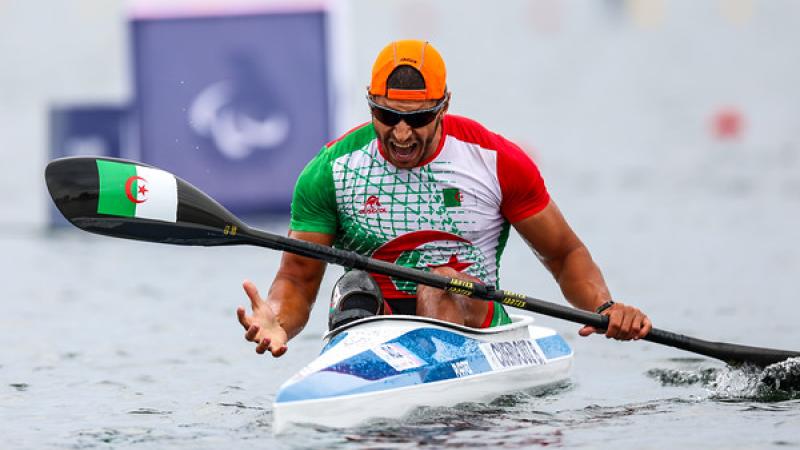A male Para canoe athlete reacting with a roar after a race