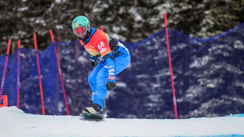 A male Para snowboard athlete is in competition.