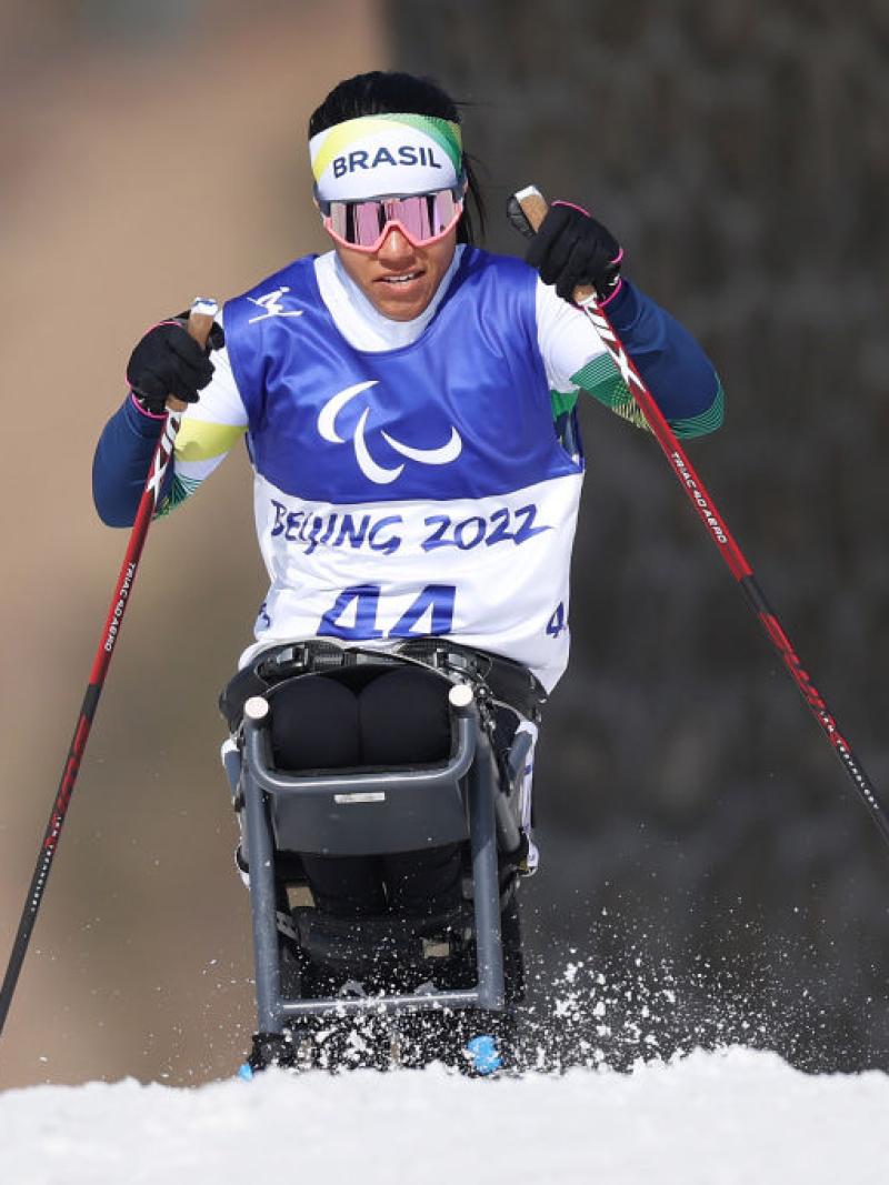 A female sit-skier is competing in a cross-country race