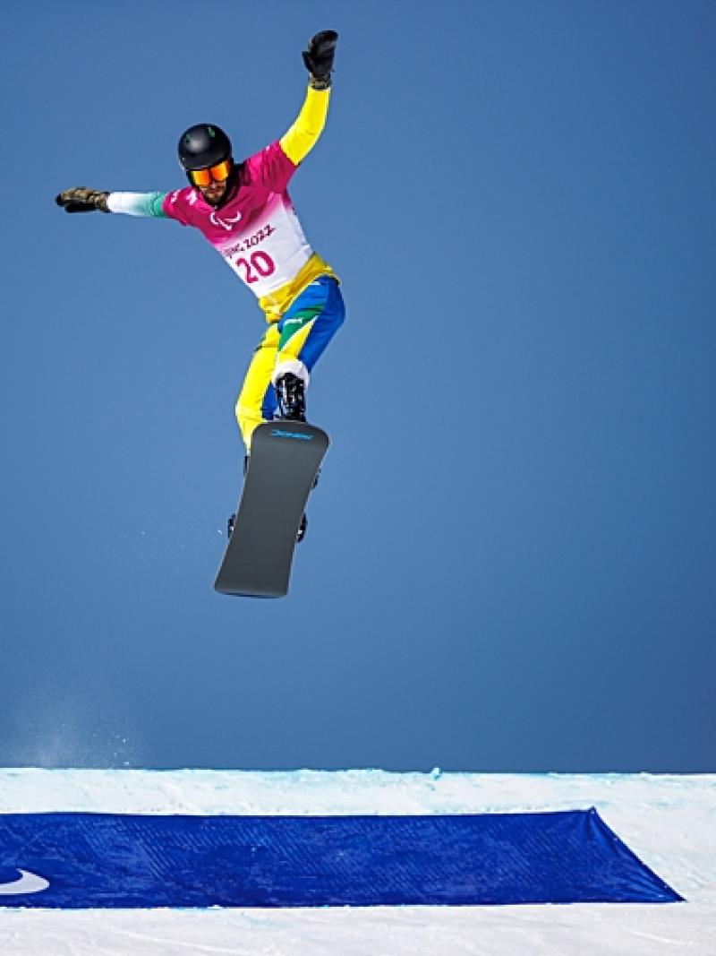 A male Para snowboard athlete makes a jump during the Beijing 2022 Paralympic Winter Games.