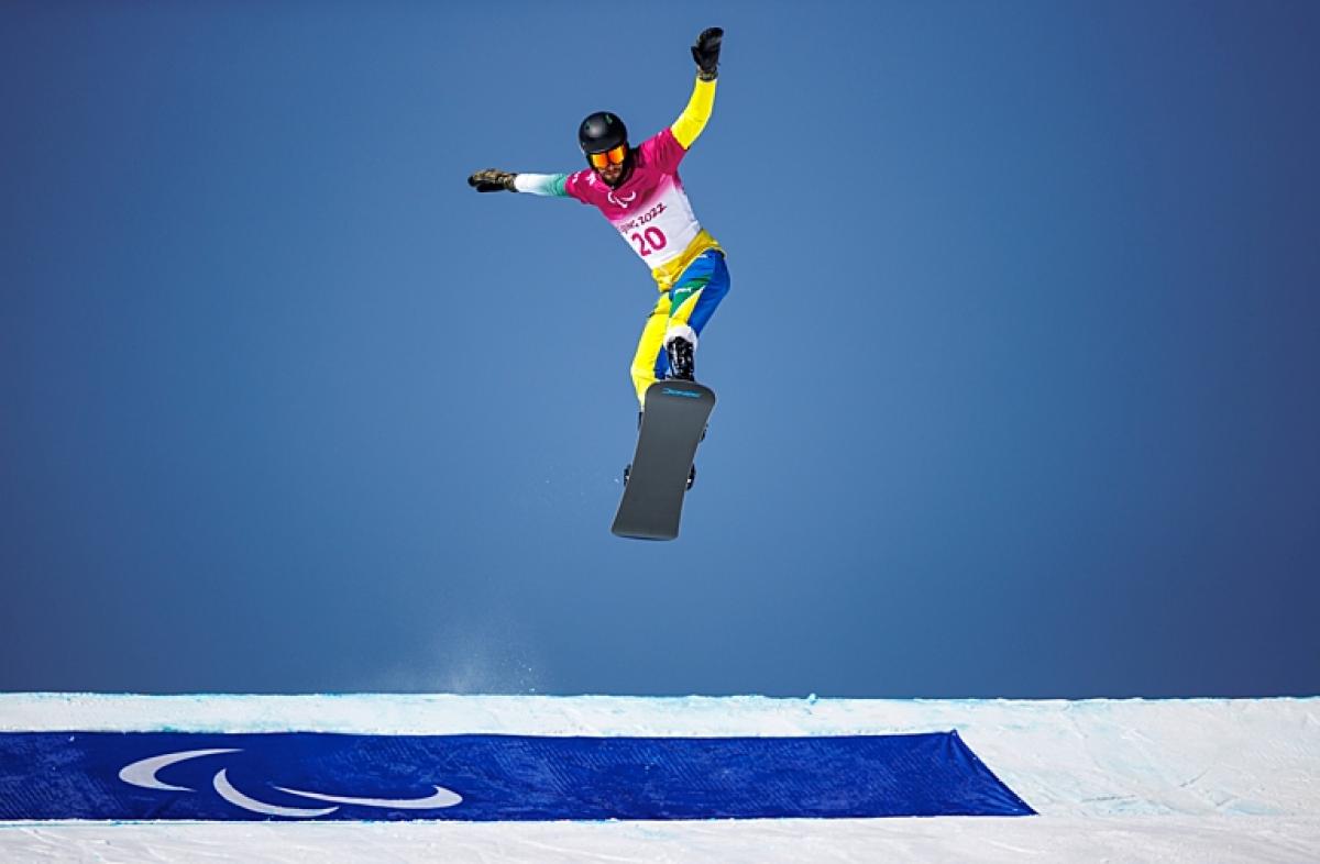 A male Para snowboard athlete makes a jump during the Beijing 2022 Paralympic Winter Games.