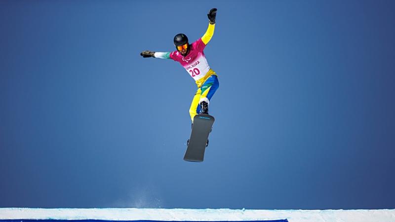 A male Para snowboard athlete makes a jump during the Beijing 2022 Paralympic Winter Games.