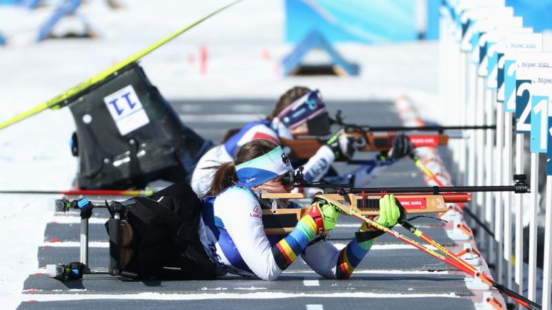A female Para biathlon athlete is competing in the shooting segment - she is aiming with a rifle