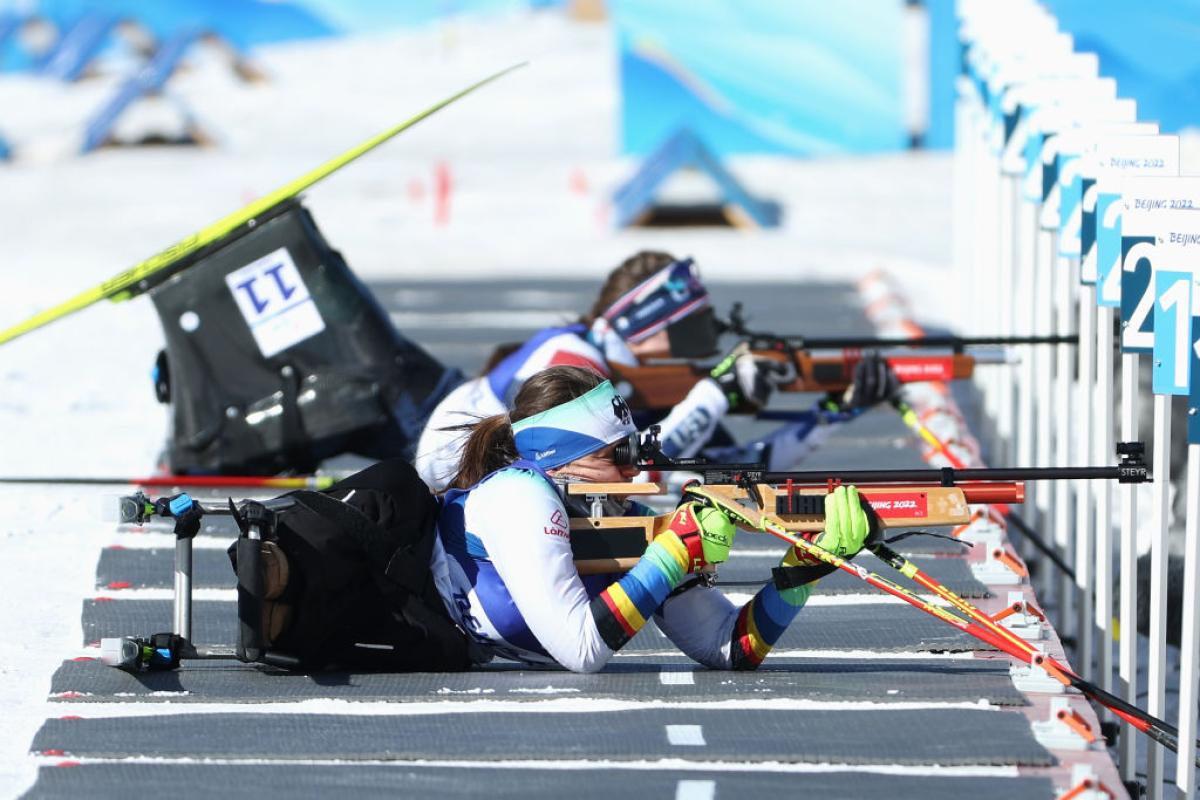 A female Para biathlon athlete is competing in the shooting segment - she is aiming with a rifle