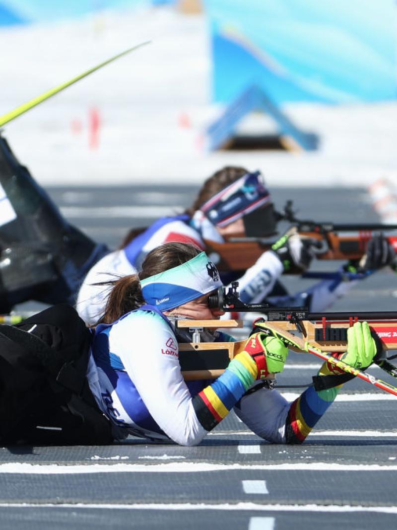 A female Para biathlon athlete is competing in the shooting segment - she is aiming with a rifle