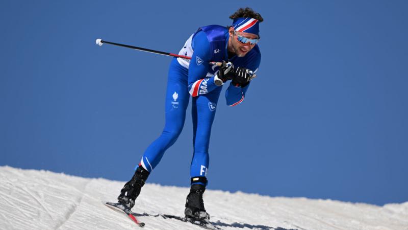 A male Para biathlon athlete is competing in cross-country skiing