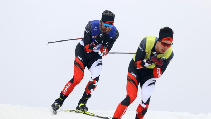 Two male Para cross-country skiing athletes in action