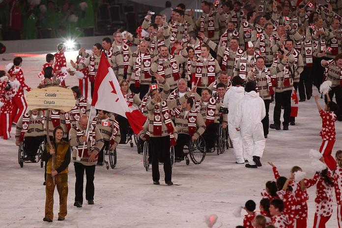 A group of Para athletes waving Canadian flags take part in the Parade of Nations