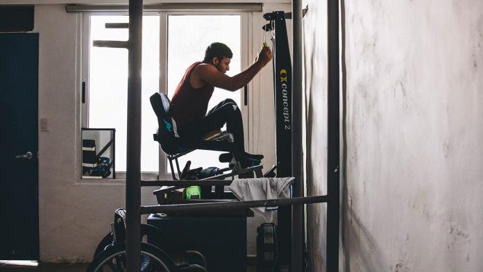 A male athlete is training using a gym equipment