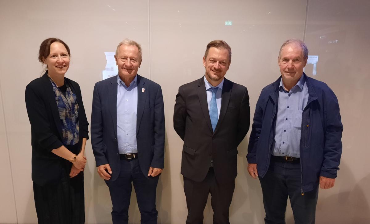 Four officials wearing formal attire pose for a photograph