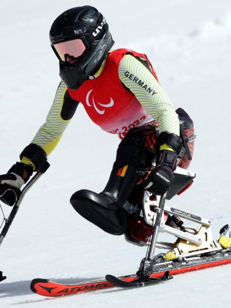 A woman races on snow in a sit ski