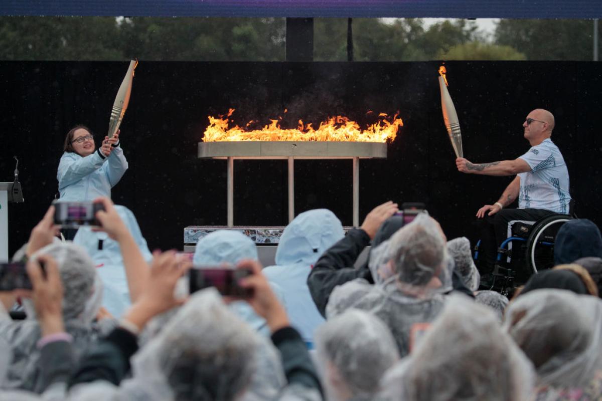 two Paralympians in wheelchairs holding up Paralympic torches