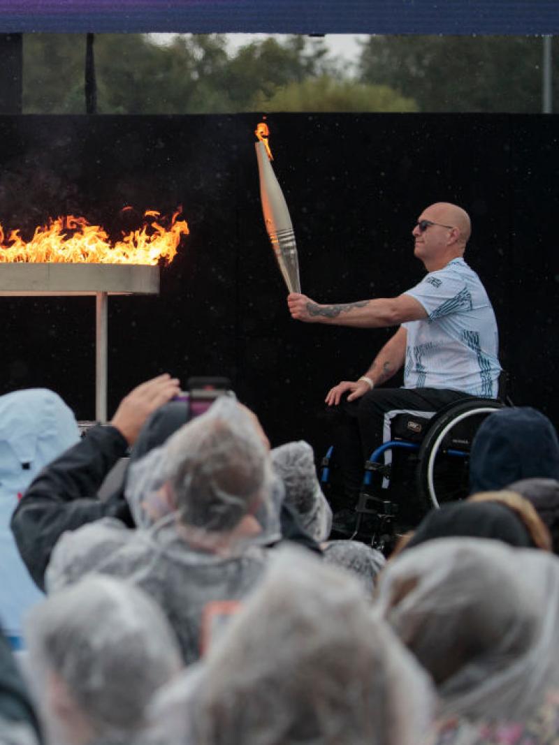 two Paralympians in wheelchairs holding up Paralympic torches