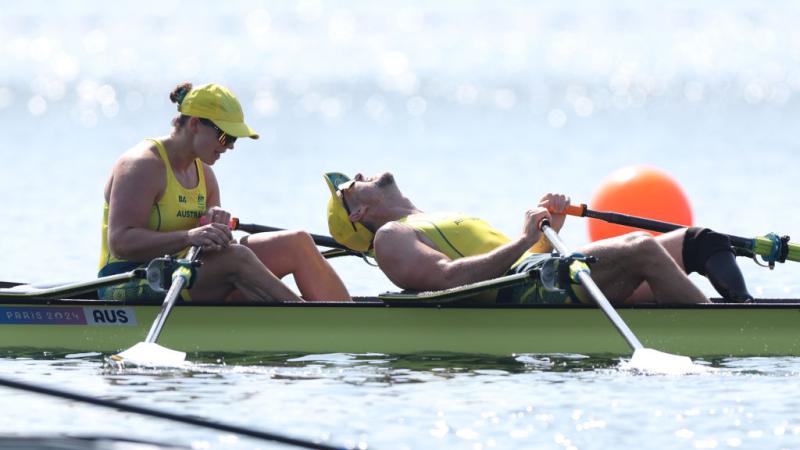 Two Australian rowers, dressed in yellow, look exhausted after winning gold in Paris