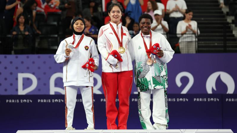 Three female Para badminton athletes with gold, silver and bronze medals on the podium