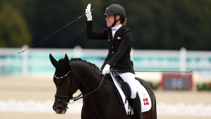 Para equestrian rider Katrine Kristensen smiles and waves on her horse