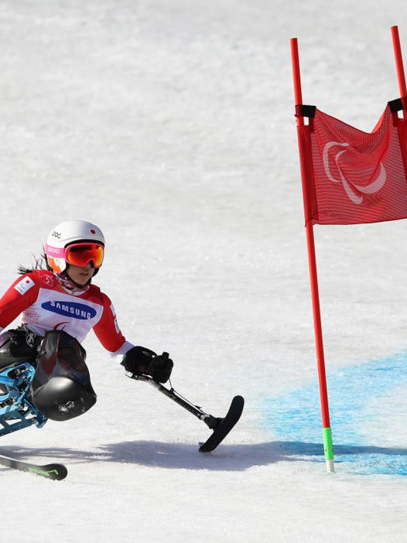 A female sit-skier crossing a flag in a giant slalom competition
