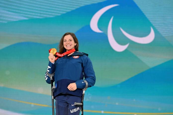 A female athlete is posing for a photo with a gold medal