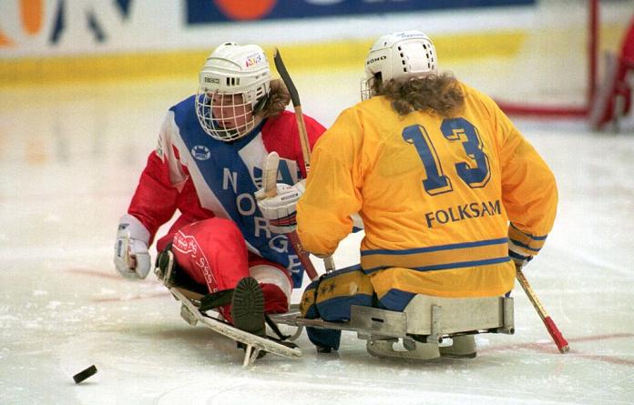 Two Para ice hockey athletes crash into each other during a game