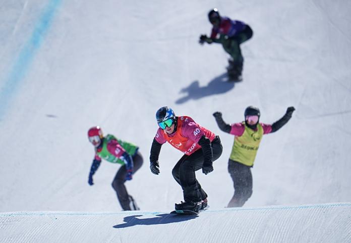 Four athletes are snowboarding 