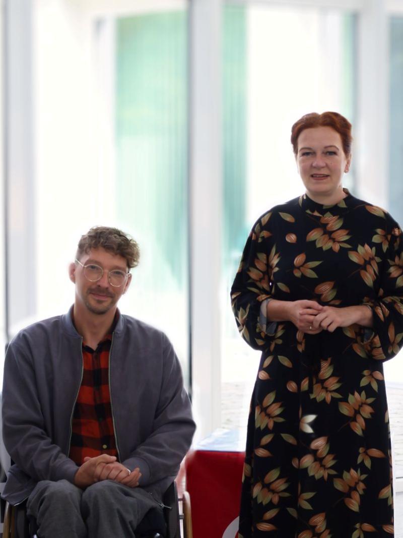 Five people pose for a photo in front of glass windows at the IPC headquarters in Bonn, Germany