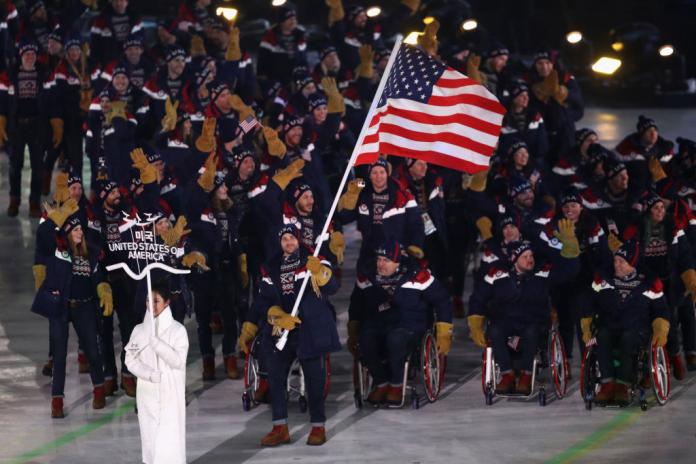 A male Para athlete is carrying the USA flag, leading the USA delegation during the PyeongChang 2018 Opening Ceremony
