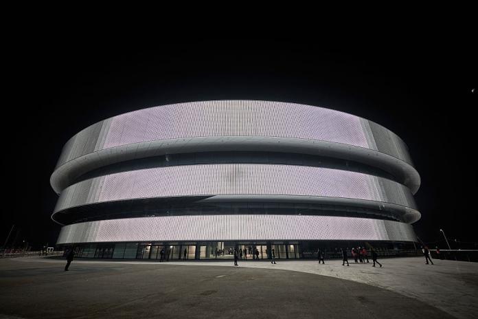 An exterior of the Milano Santagiulia Ice Hockey Arena, which is a dome-shaped venue with glass doors