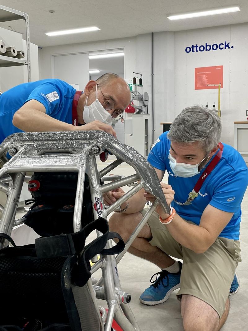 Two men wearing Ottobock shirts fixing a wheelchair