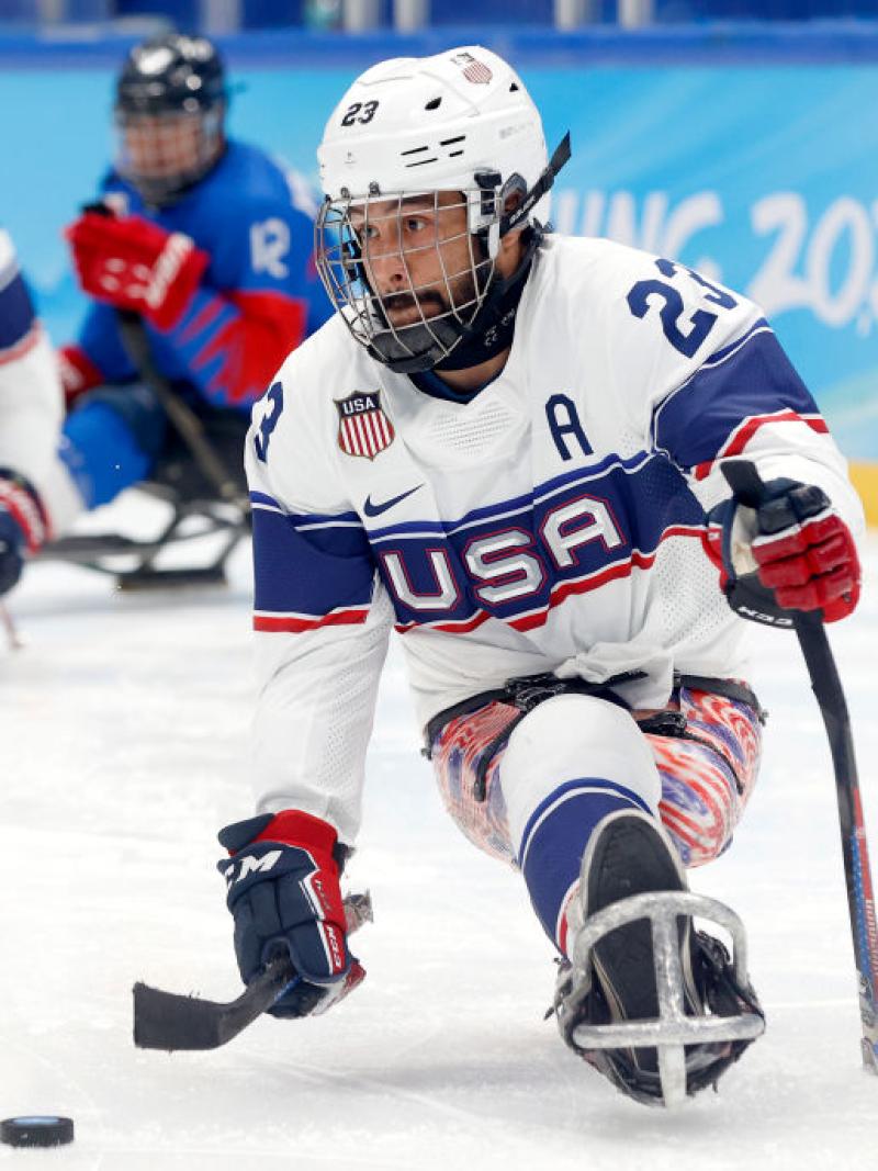 A male Para ice hockey player is in action - he is about to shoot a hockey puck