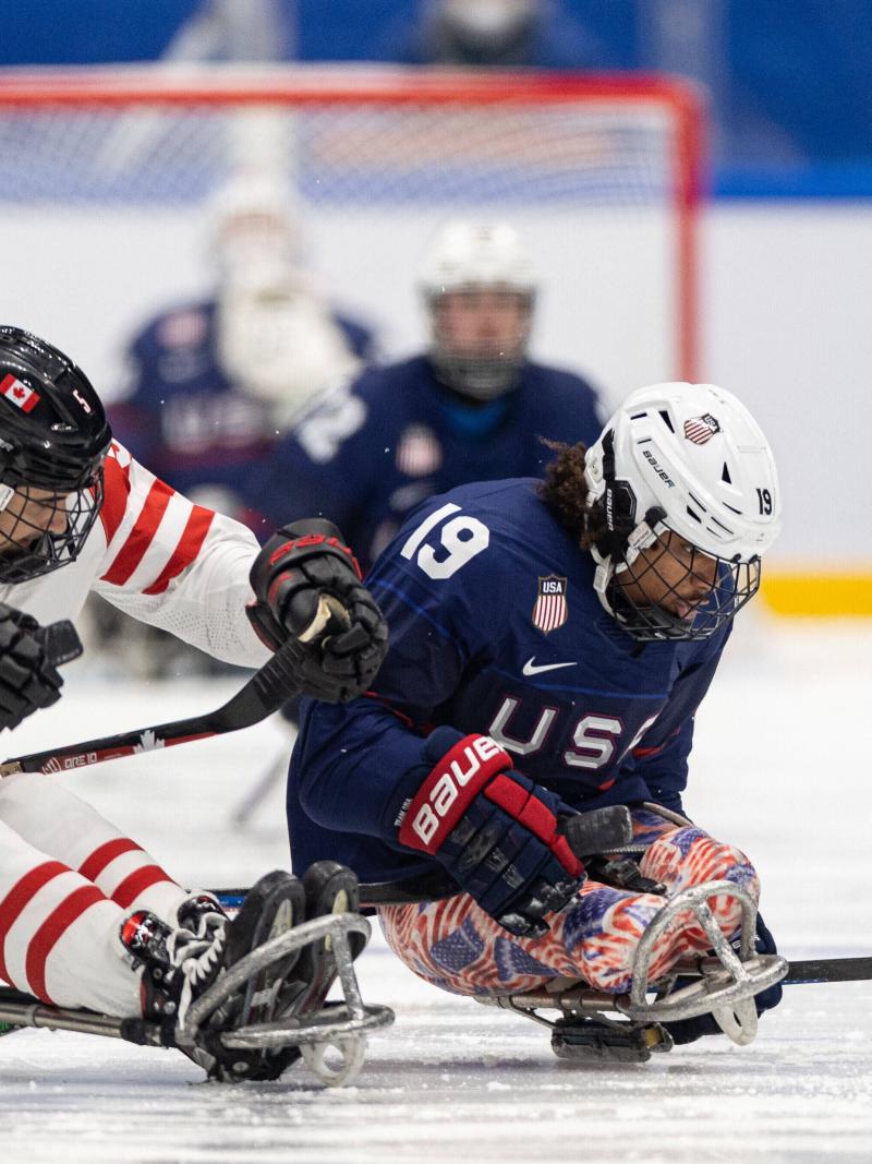 Two Para ice hockey players in full gear fighting for the possession.