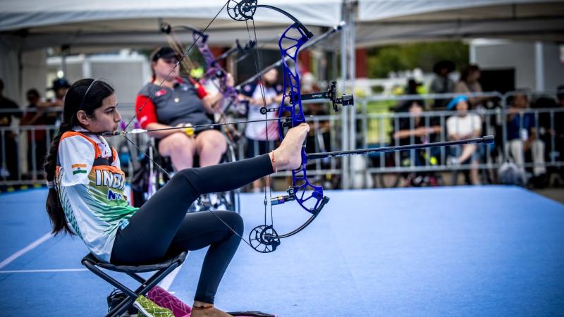 A female Para archer shoots an arrow using her right leg and chin