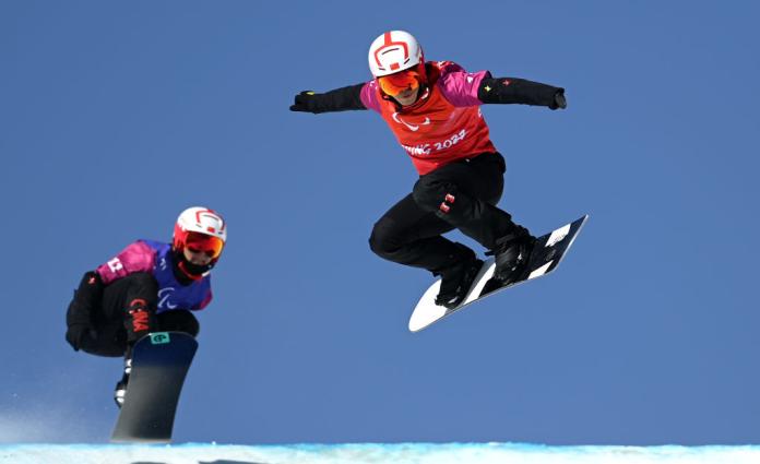 Two Para snowboarders are side-by-side competing against each other